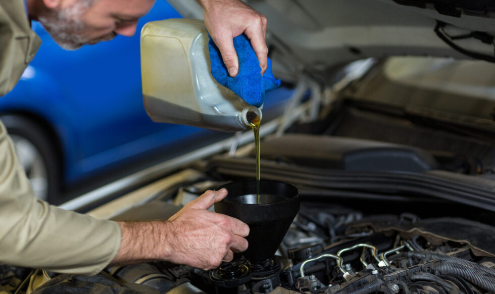 Mechanic pouring oil into car engine car oil change service in dubai